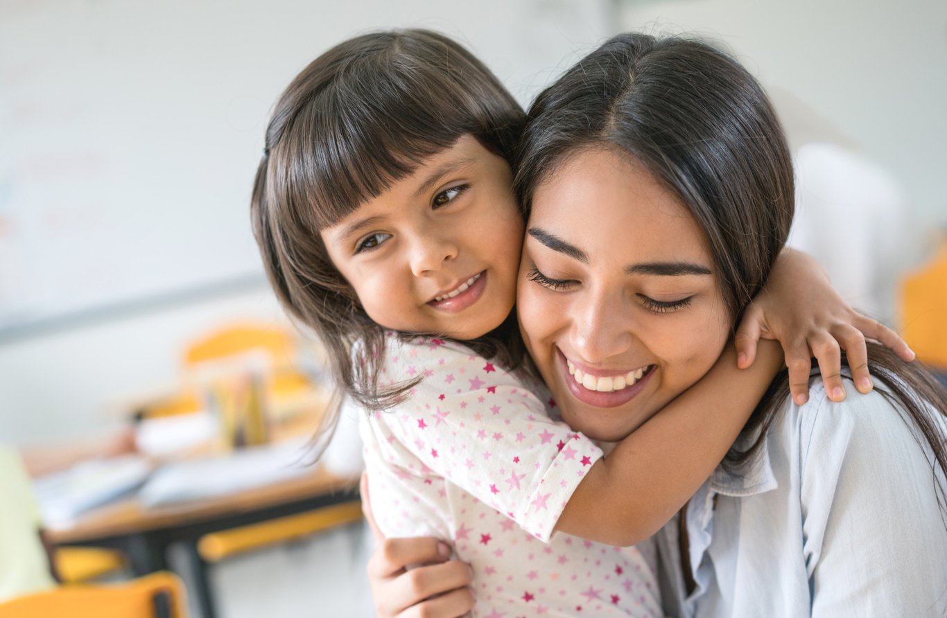 Portrait of an affectionate teacher hugging a young student